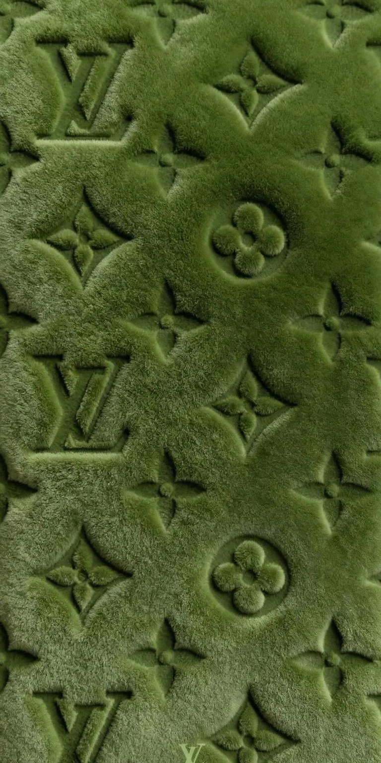 Download this mesmerizing Louis Vuitton 4K wallpaper for your iPhone, featuring a textured green surface. The iconic LV logo and flower patterns create a luxurious wallpaper.