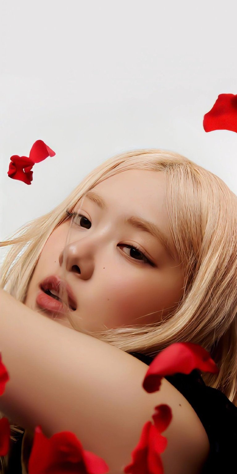Download this stunning Rosé wallpaper in 4K for your iPhone, featuring red rose petals scattered around her face. Her blond hair and soft makeup details make this wallpaper pop!