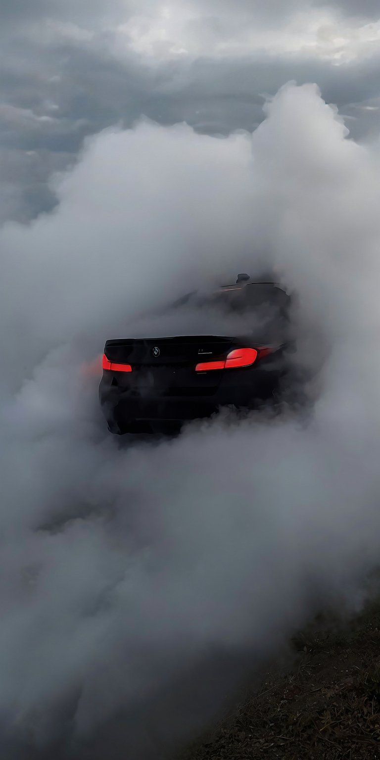 Get this BMW 4K wallpaper for your iPhone, featuring the car engulfed in a cloud of smoke with its taillights visible. This stunning wallpaper captures the essence of power and performance.