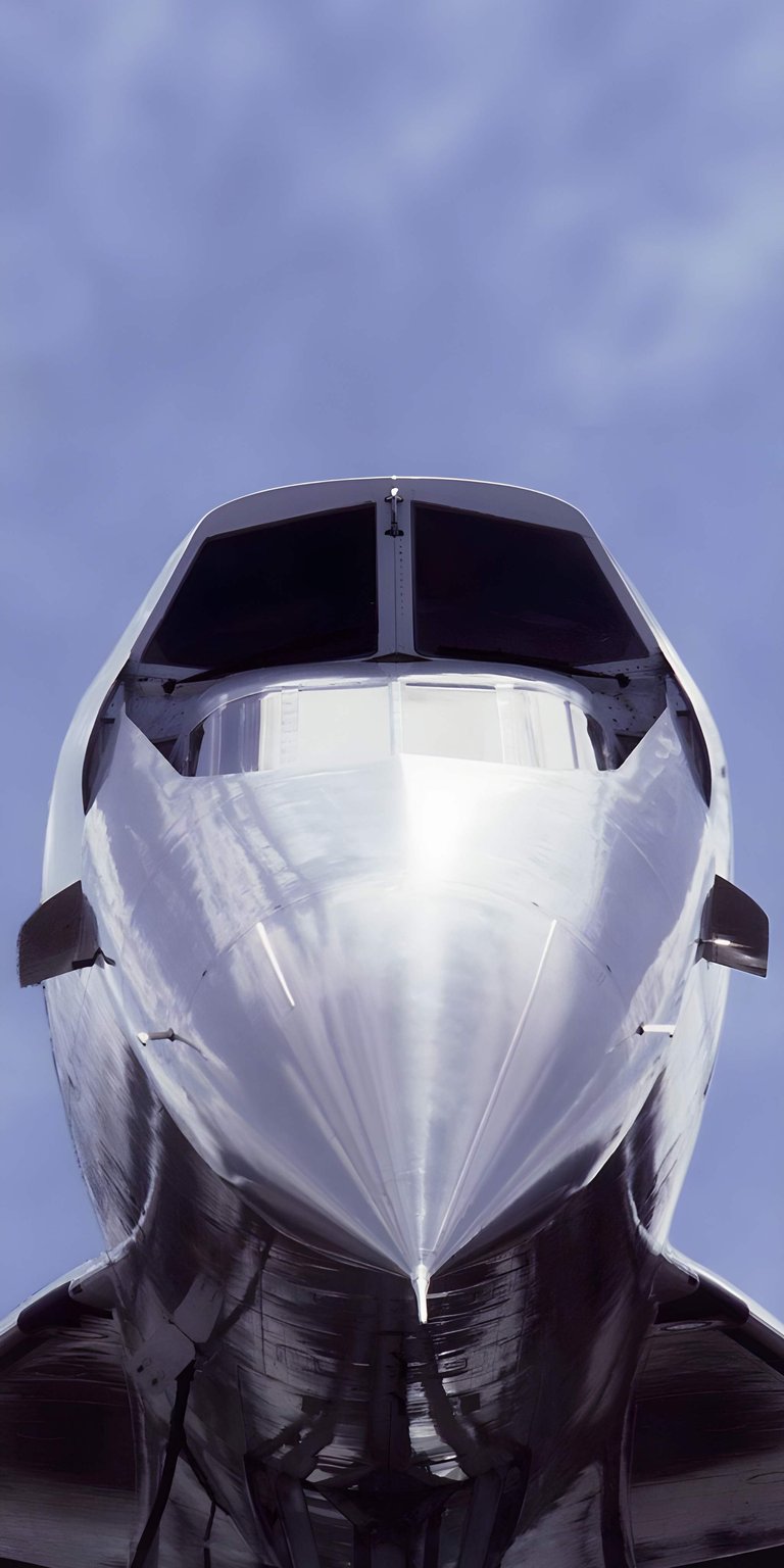 This high-resolution 4K wallpaper features a dramatic low-angle shot of the iconic Concorde nose and visor. Designed specifically for iPhone, this aesthetic wallpaper captures the polished silver fuselage and sharp geometric lines against a soft blue sky.