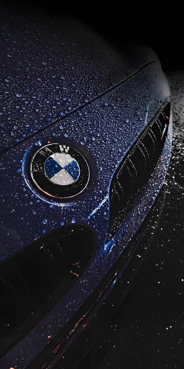 This striking OLED wallpapers selection features a close-up of a blue BMW emblem covered in fresh raindrops against a deep black background. Optimize your iPhone with this high-contrast wallpaper that highlights sparkling textures and a moody, premium automotive aesthetic.