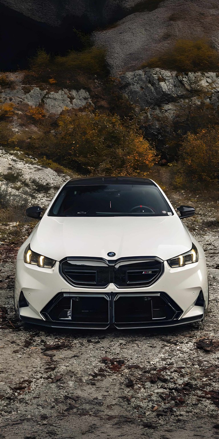 This White BMW M2 G87 4K wallpaper captures the aggressive stance and modern design of the luxury coupe against a rugged mountain landscape. Designed specifically for iPhone, this aesthetic wallpaper highlights the high-contrast black accents and sharp LED lighting of the vehicle.