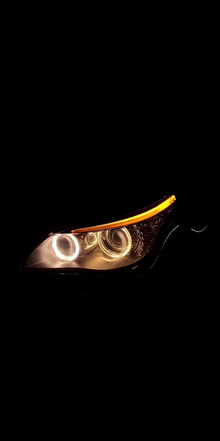 Get this stunning BMW 4K wallpaper for your iPhone, showcasing a striking headlight. This wallpaper highlights the intricate spiral detailing within the headlight lens and the glowing amber light strip.