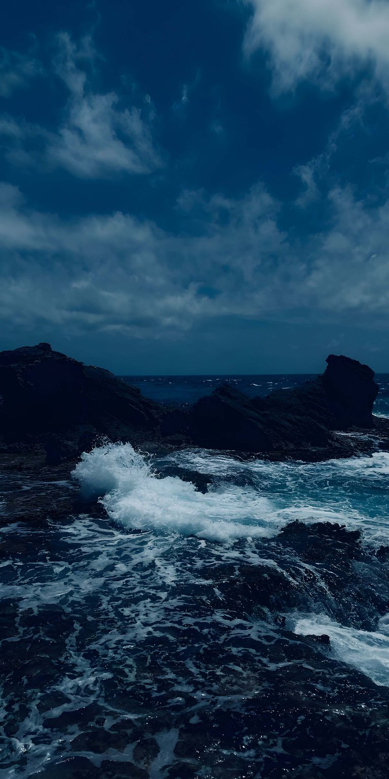 Get this stunning ocean rocks 4K wallpaper for your iPhone. Featuring dramatic waves crashing against dark rocks and a moody, clouded sky, this wallpaper will make your device stand out.
