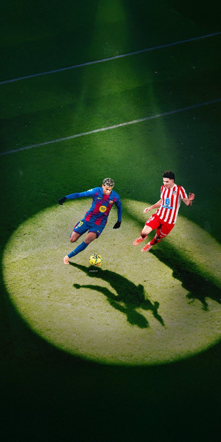 Experience the intense drama of a top-tier football match with this striking live wallpaper. Captured under a powerful, focused stadium spotlight, the image features two elite players—one in a blue and red kit (reminiscent of FC Barcelona) and the other in a red and white striped kit (like Atlético Madrid)—locked in a high-stakes duel for the ball. The strong lighting casts long, dramatic shadows across the grass pitch, emphasizing the speed, energy, and competitive spirit of the moment. Perfect for any football fan, this wallpaper brings the thrill of La Liga action and a unique, cinematic aesthetic to your device.