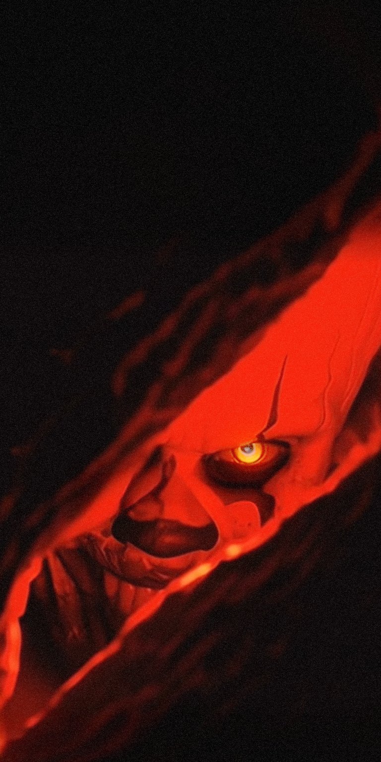 Get this terrifying It clown 4K wallpaper for your iPhone, featuring his menacing gaze and vibrant red makeup. This wallpaper captures the essence of fear with the clown's intense yellow eye and the dark shadows surrounding him.