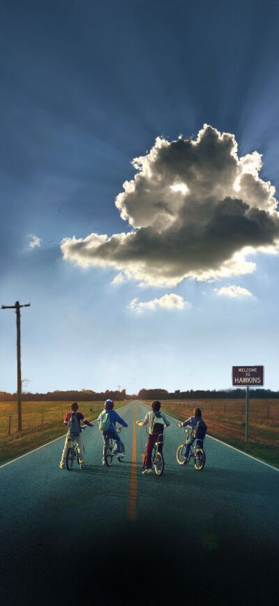 Get this Stranger Things wallpaper in 4K for your iPhone! This matching wallpaper, perfect for two people, features a group of kids riding their bikes down a road, with a welcoming sign of Hawkins and an interesting cloud above.