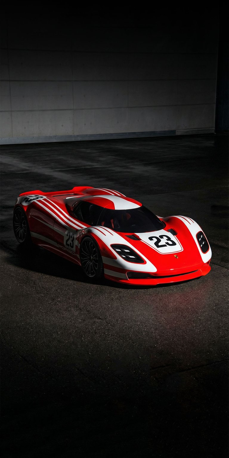 A striking 4K wallpaper featuring the Porsche 917 Living Legend concept car in a high-contrast studio setting. This OLED / AMOLED wallpapers design for iPhone emphasizes the car's aggressive red and white racing livery against a deep, pitch-black background.