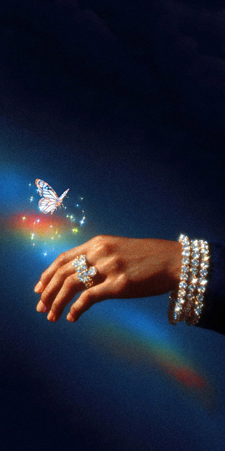 An elegant and ethereal wallpaper showcasing a hand adorned with a luxury diamond ring and a sparkling iced-out bracelet. A shimmering butterfly rests on the finger, trailing a magical rainbow prism and glittering dust against a deep blue gradient. This wallpaper radiates luxury, magic, and high-fashion "clean girl" aesthetics.