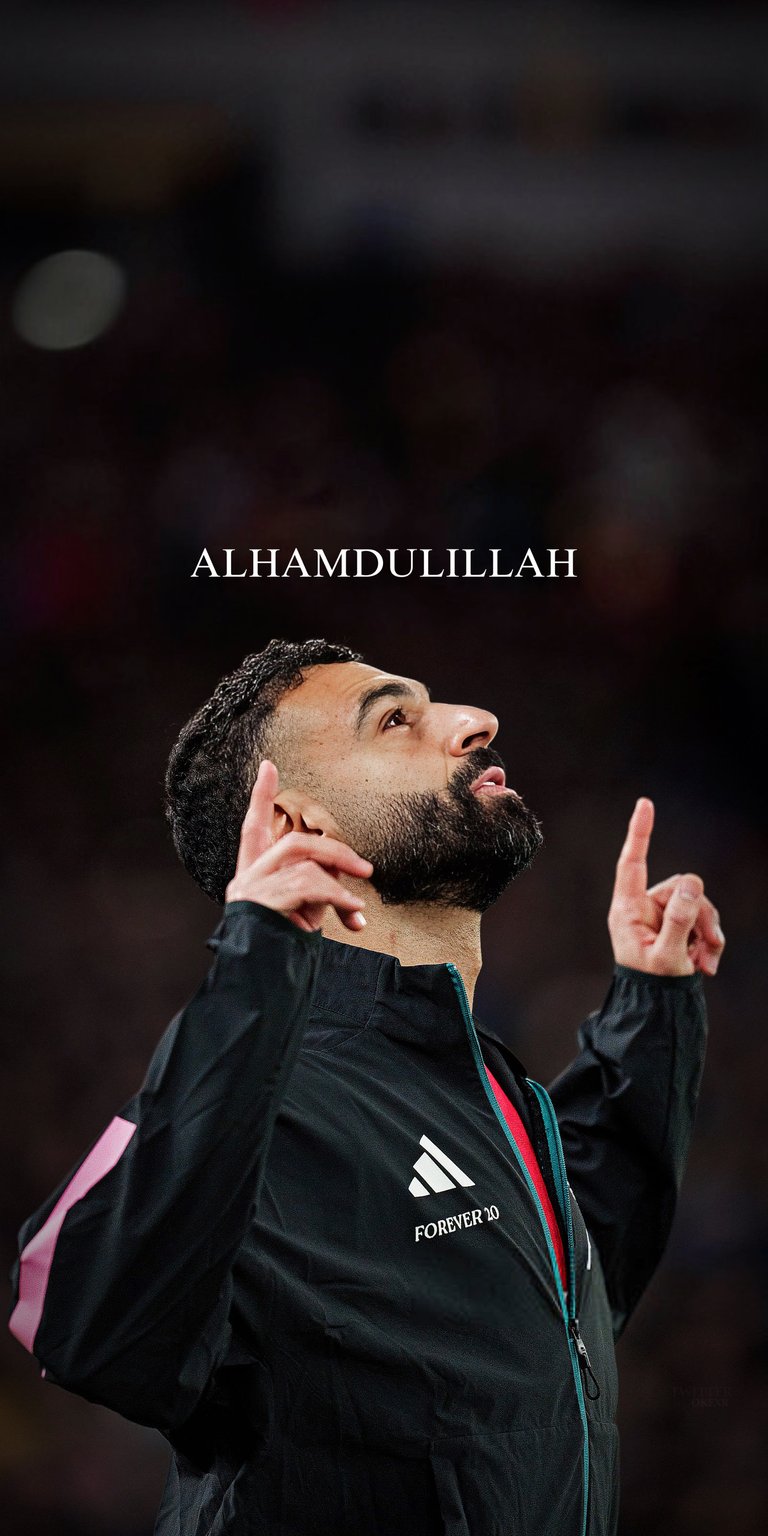 Mohamed Salah 4K Wallpaper features the football star in a dark sports jacket with bold lighting and a powerful upward gesture. This aesthetic wallpaper stands out on iPhone, making the wallpaper perfect for lock screen and home screen.