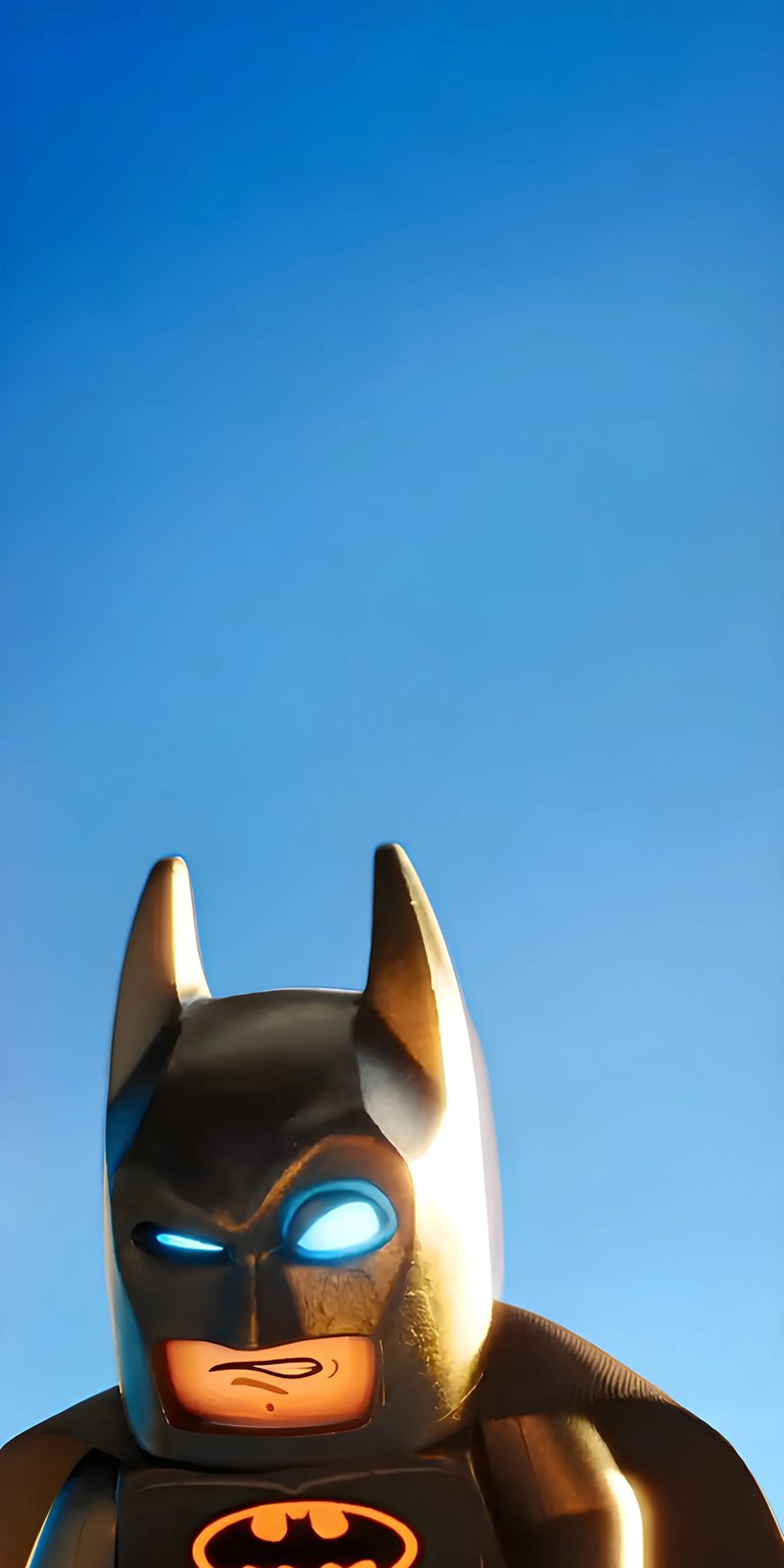 Download this Lego Batman 4K wallpaper for your iPhone today! This wallpaper features the Lego Batman character with glowing blue eyes, set against a clear blue sky, creating an awesome wallpaper for your phone.