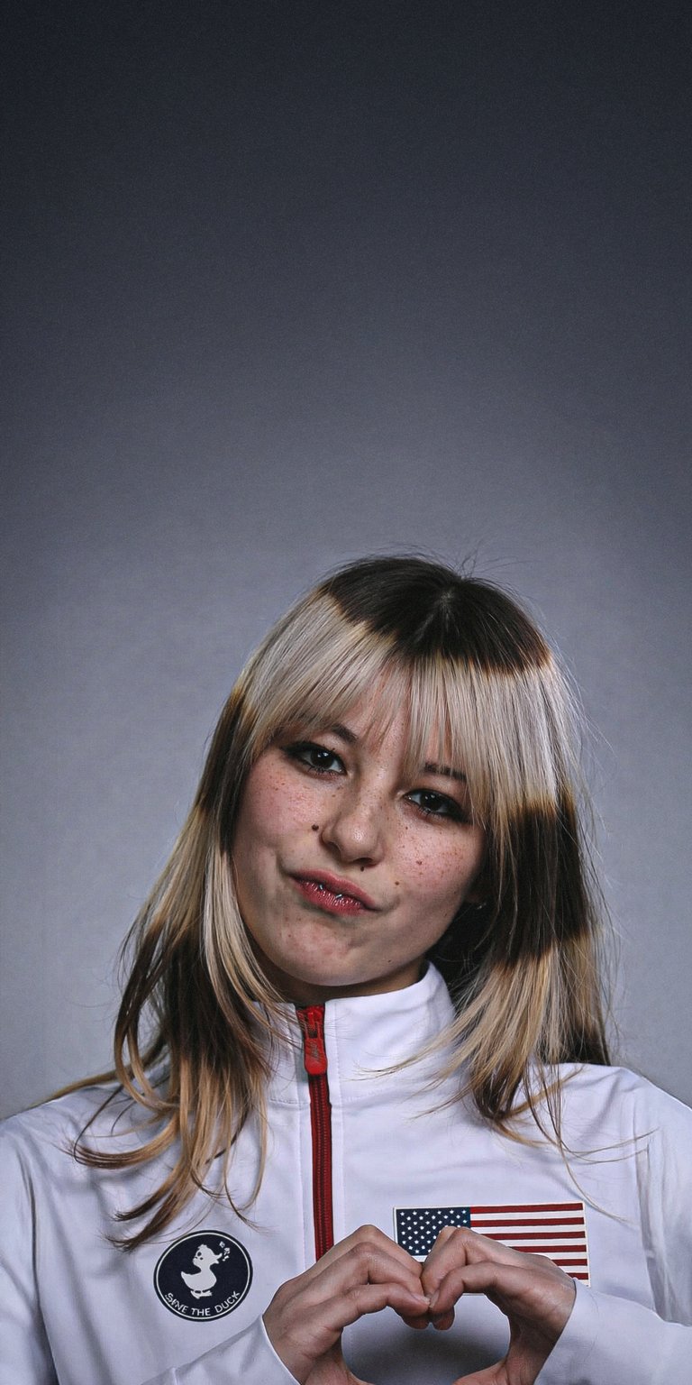 This 3D wallpaper features a clean portrait of figure skater Alysa Liu in team gear. It offers a professional and bright aesthetic for your iPhone lock screen.