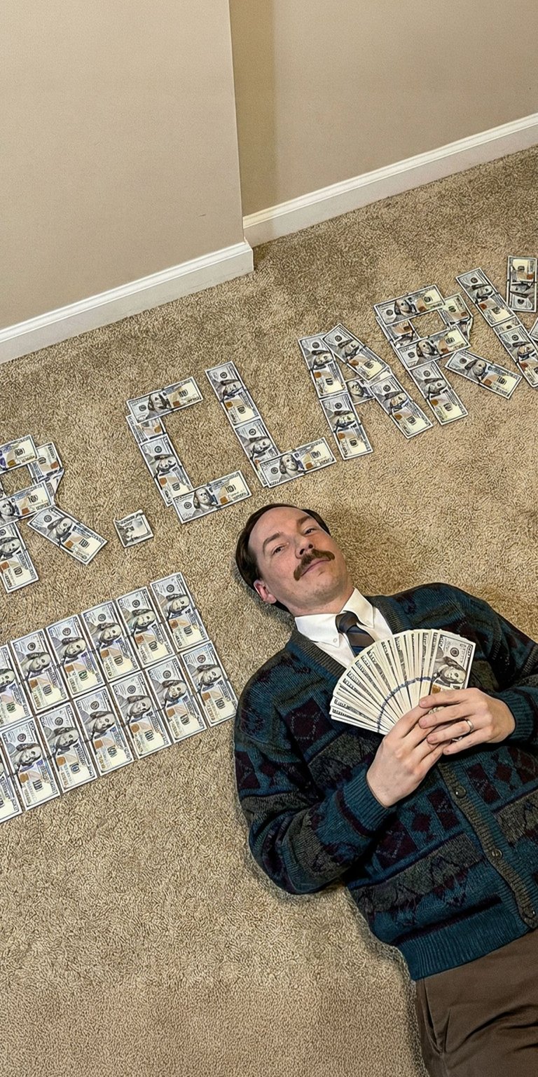 Download this awesome Mr. Clarke wallpaper in 4K for your iPhone! This wallpaper features Mr. Clarke lying on a carpet covered in cash, fanning himself with more money, wearing a stylish cardigan.