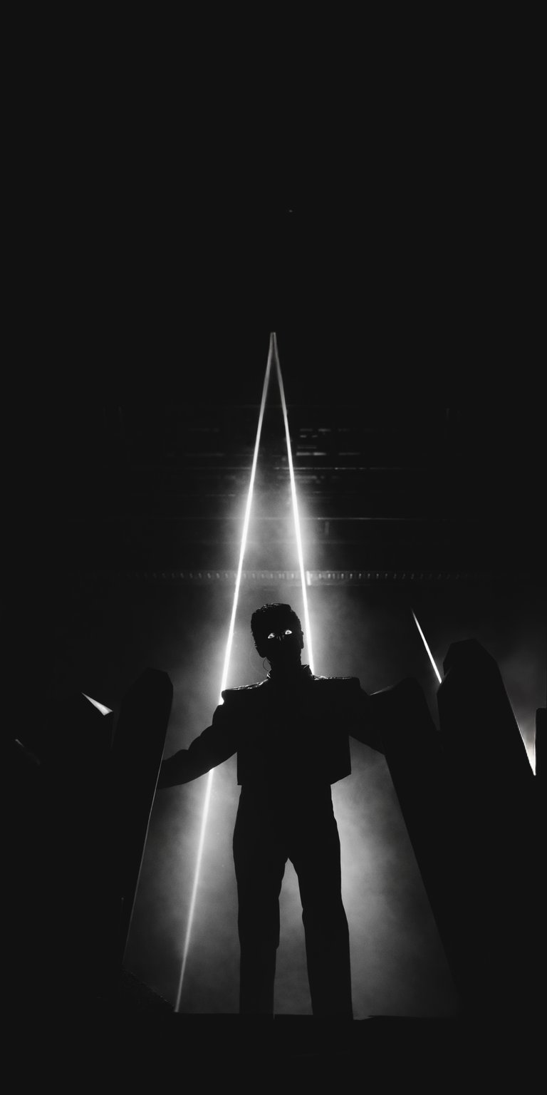 This high-contrast 4K wallpaper features a dramatic silhouette of The Weeknd framed by piercing stage lasers. Perfect for your iPhone, this entry in our OLED wallpapers collection uses deep blacks and brilliant white light to create a minimalist, cinematic mood.