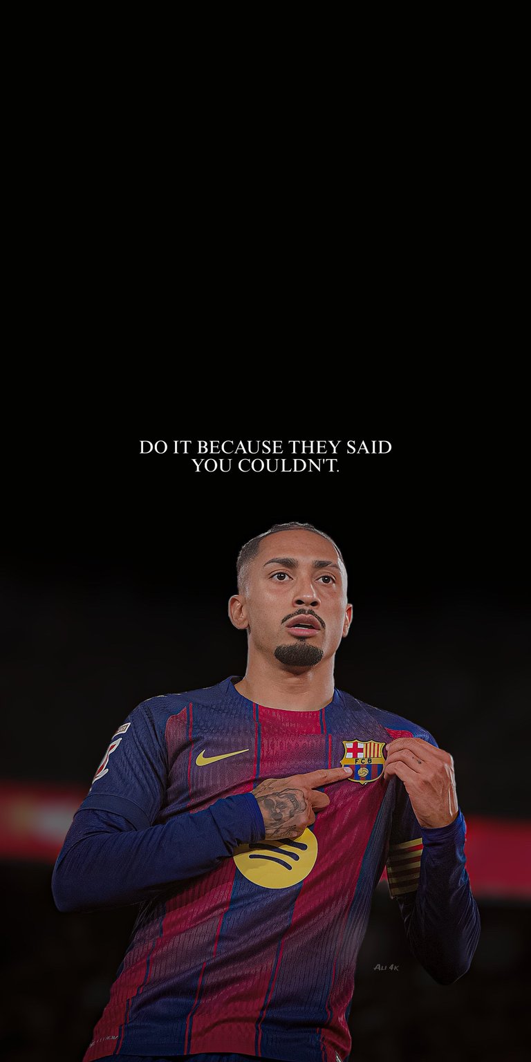 This Raphinha 4K wallpaper is optimized for iPhone displays using deep black tones characteristic of OLED wallpapers. The design features the player pointing to the FC Barcelona crest beneath a bold, centered motivational quote.