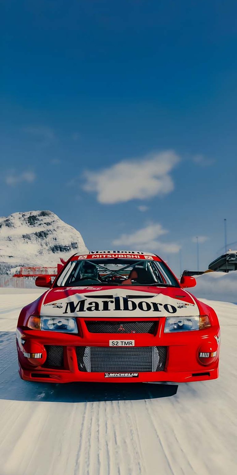 Get this stunning Mitsubishi Lancer wallpaper in 4K for your iPhone! The red rally car with the Marlboro logo is seen drifting on a snow-covered track, set against a backdrop of mountains and a blue sky.
