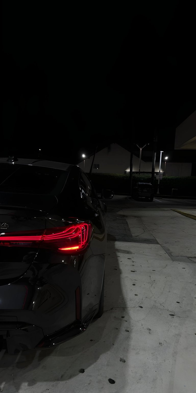 A moody, late-night shot focusing on the aggressive rear design and glowing LED tail lights of a BMW M5. Set against a dark urban parking lot, this wallpaper highlights the sleek lines and premium engineering of German automotive design. Perfect for car enthusiasts who prefer a "dark mode" aesthetic.