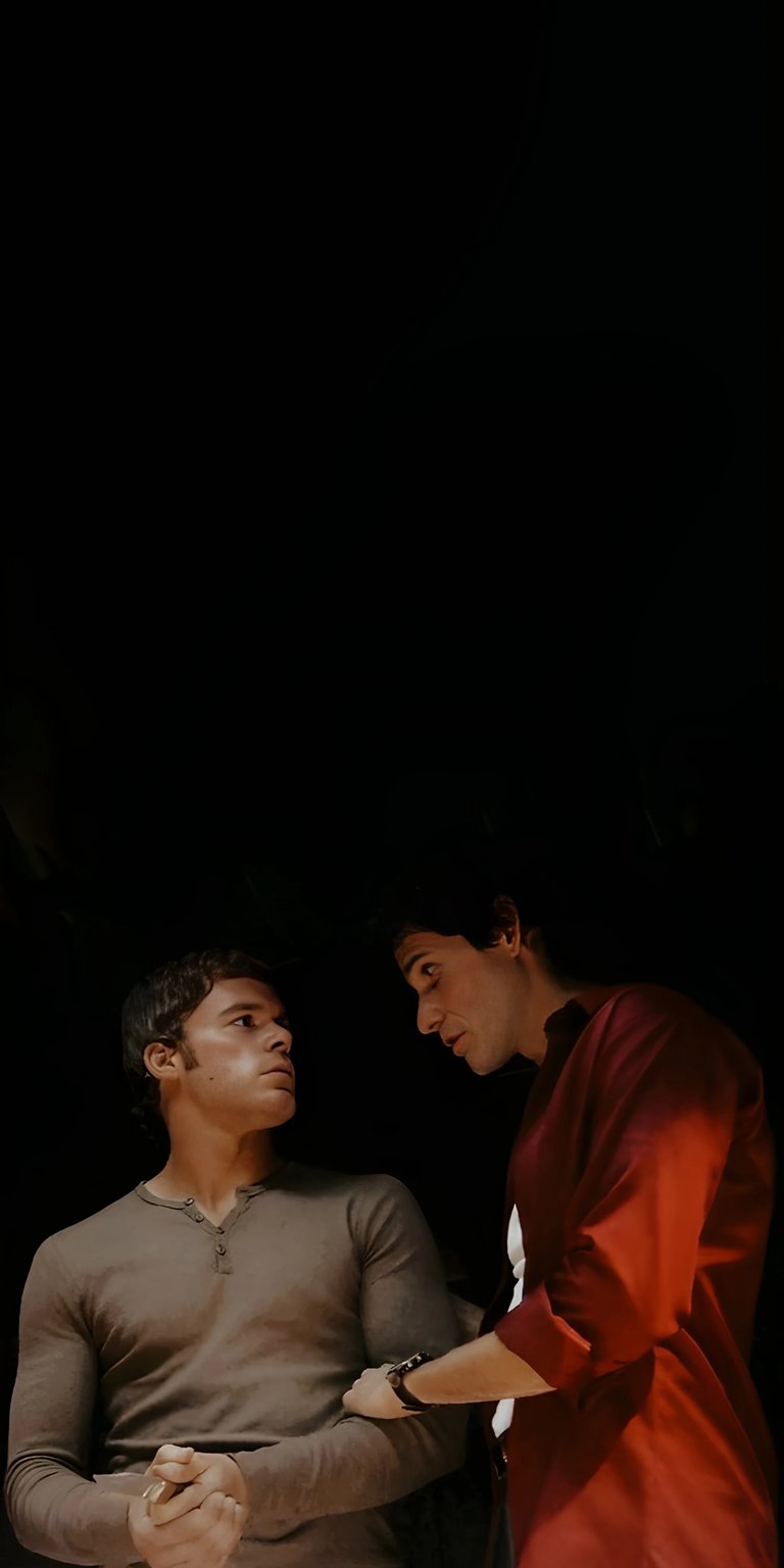 Download this striking Dexter Morgan and Brian Moser 4K wallpaper for your iPhone. The dramatic lighting emphasizes Miguel's bright red shirt and Dexter's clasped hands.