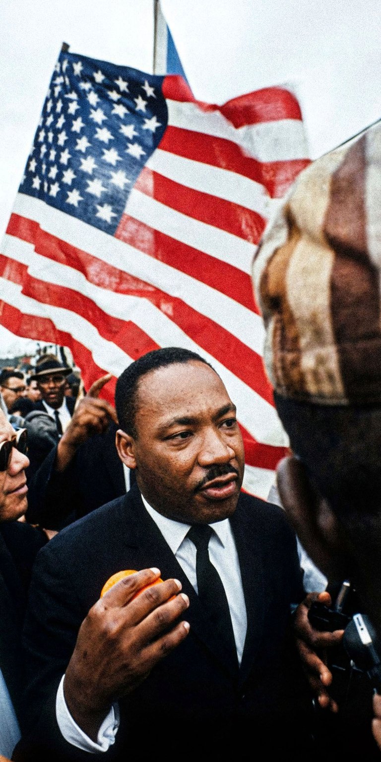 This historic wallpaper features Martin Luther King Jr. standing before the American flag. A powerful aesthetic wallpaper designed for your iPhone lock screen.
