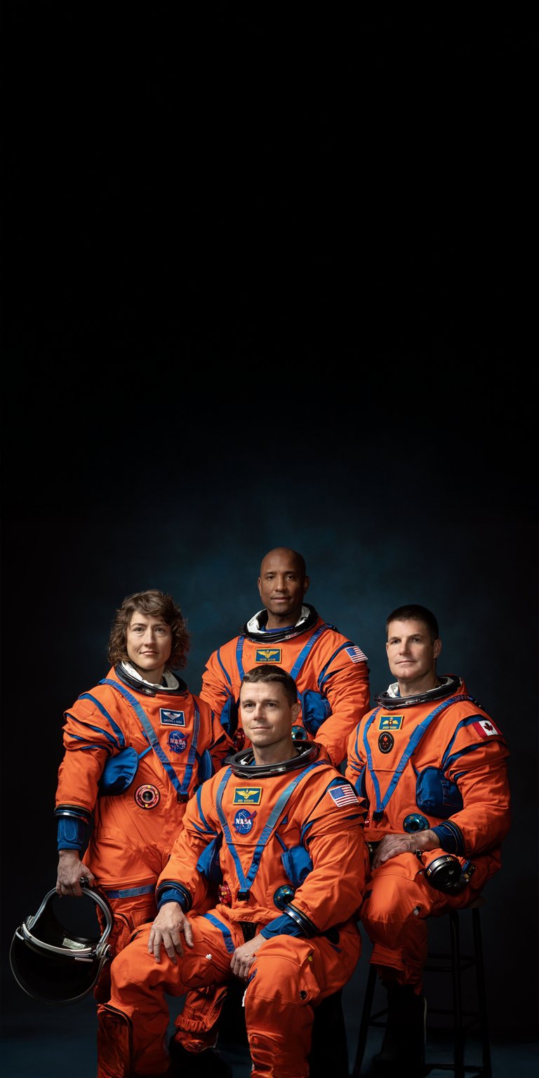 Display the future of lunar exploration with this official Artemis II crew portrait wallpaper designed for mobile screens. This high-resolution 4K wallpaper showcases the four-person astronaut team in vibrant orange suits with sharp, professional studio lighting.