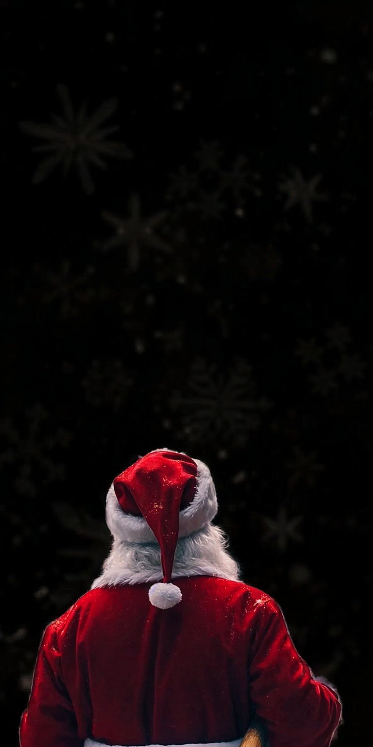 Download this festive Santa Claus wallpaper in 4K for your iPhone. This wallpaper features Santa from behind in his red suit, walking in a winter wonderland with snowflakes falling behind him.