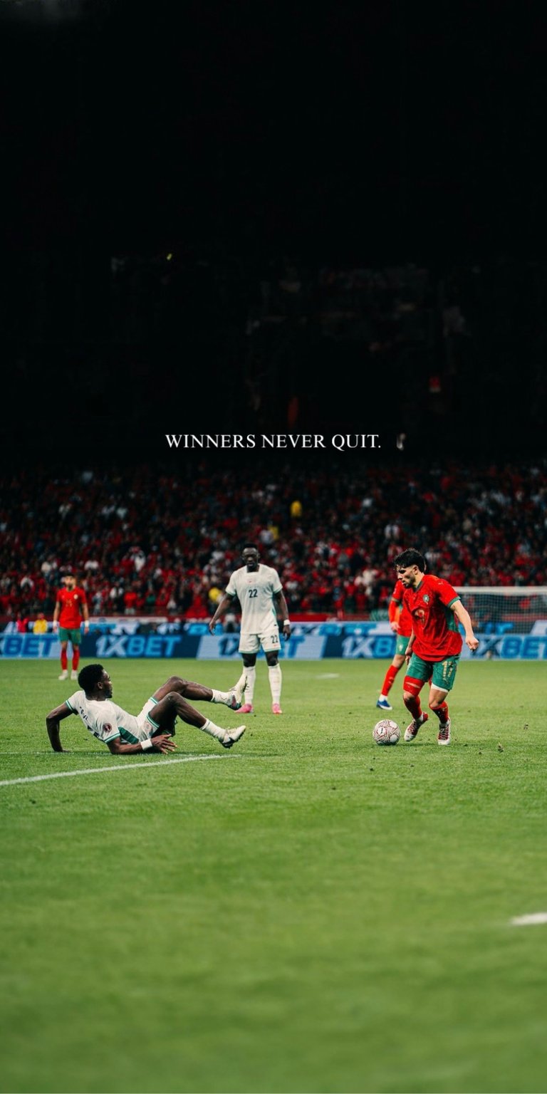 Get this Abde Ezzalzouli 4K wallpaper showing the Moroccan winger in intense match action on the pitch. This iPhone wallpaper features "Winners Never Quit" typography over a high-energy stadium background with vivid green grass.