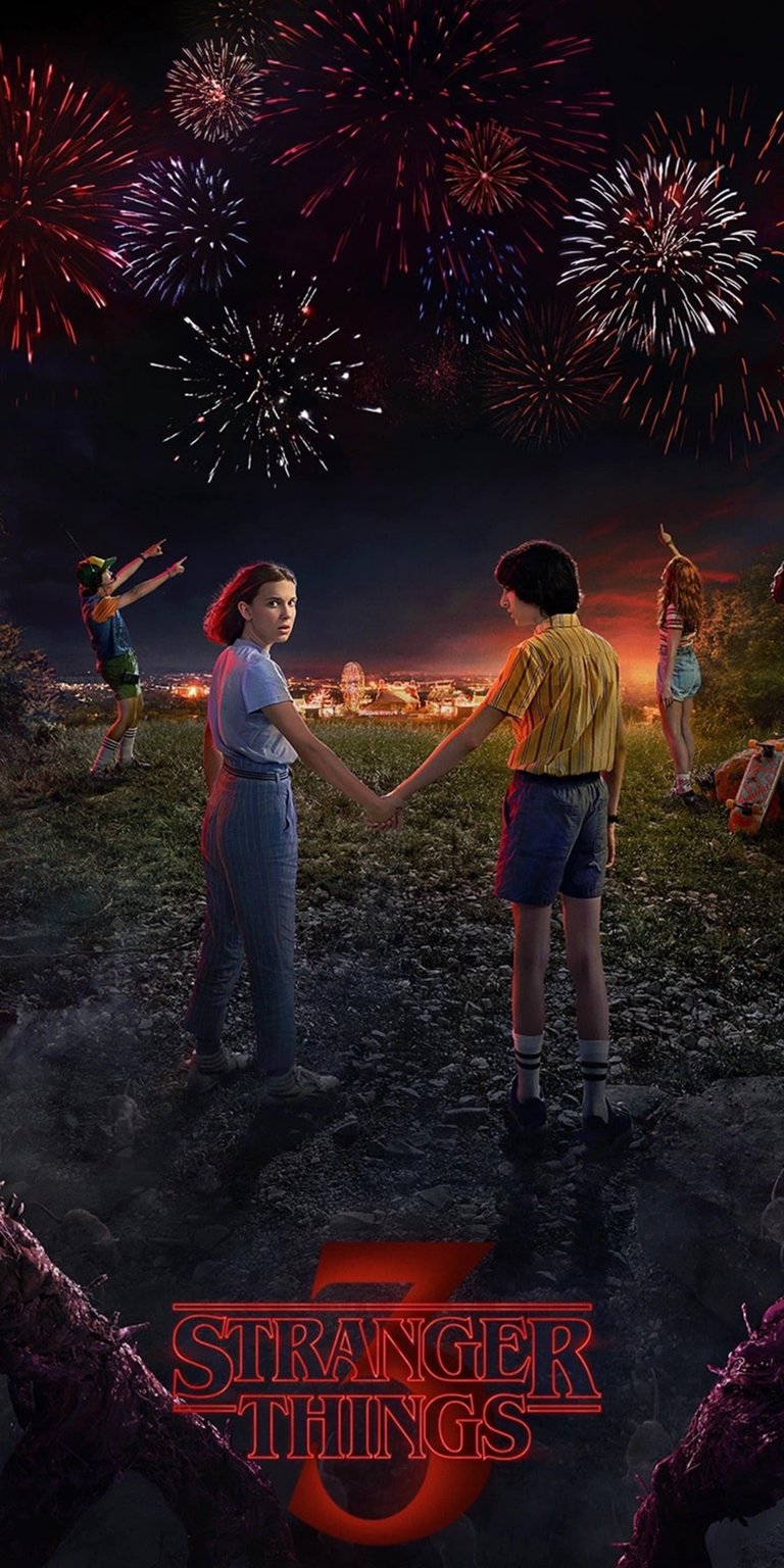 Download this striking Stranger Things 4K wallpaper for your iPhone, showcasing Eleven and Mike holding hands against a backdrop of vibrant fireworks. The eerie vines at the bottom and kids pointing towards the fireworks add to the mysterious charm, making this wallpaper a must-have.