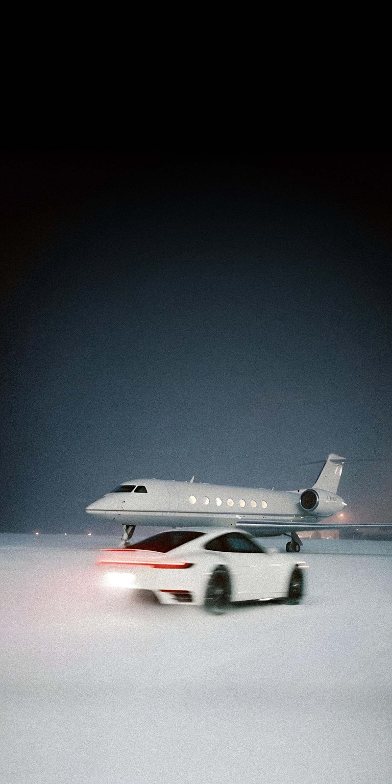 A cinematic shot of a white Porsche 911 speeding across a frozen tarmac toward a waiting private jet. The motion blur and monochromatic winter palette evoke a sense of urgency and elite travel.