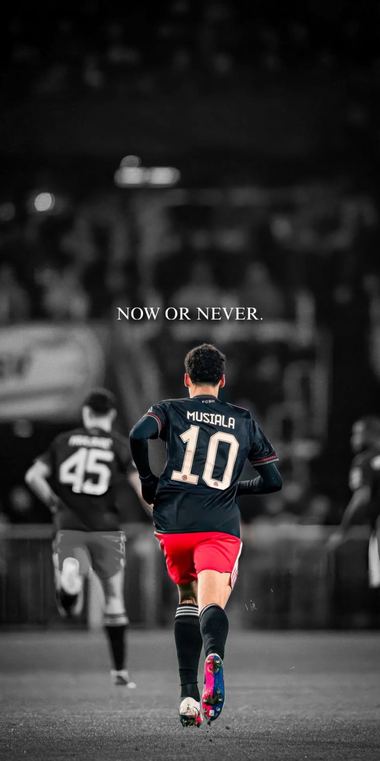 This 4K Aesthetic wallpapers design features Jamal Musiala on the pitch for your iPhone. The wallpaper highlights a selective color effect with red accents against a moody, desaturated stadium background.