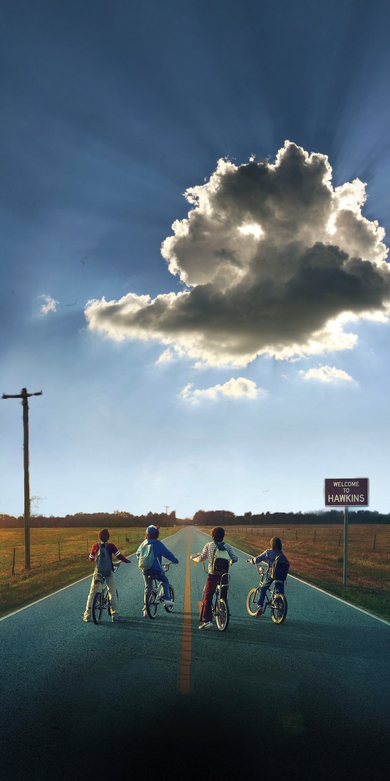 Download this Stranger Things 4K wallpaper for your iPhone, showing the group of friends on their bikes riding towards the "Welcome to Hawkins" sign under a partly cloudy sky. This nostalgic wallpaper captures the essence of the show with the sun rays bursting through the clouds.