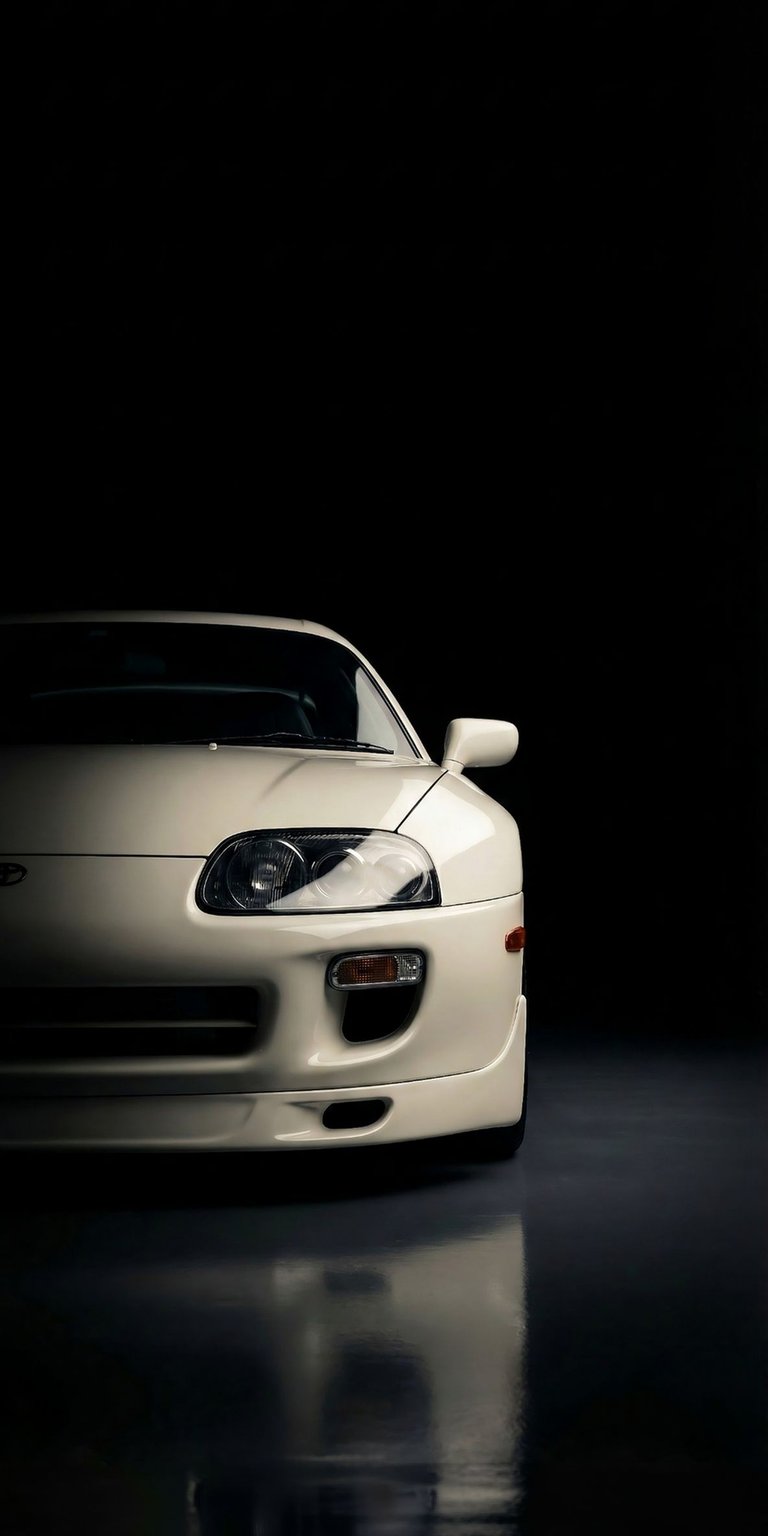 This high-contrast Toyota Supra MK4 wallpaper features a clean white finish against a deep black background, perfect for OLED / AMOLED wallpapers. The 4K image highlights the iconic front-end design and reflective surfaces for a premium look on your iPhone.