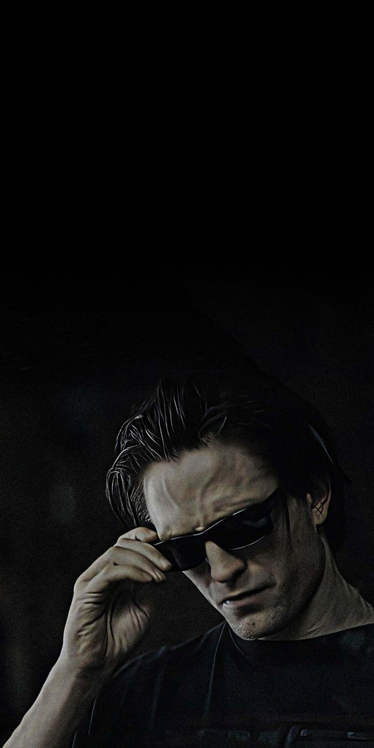 Get ready to upgrade your iPhone with this stunning Robert Pattinson 4K wallpaper, featuring the actor in a casual black t-shirt and modern sunglasses. This wallpaper captures the cool confidence of Robert Pattinson with his hand casually adjusting his sunglasses.