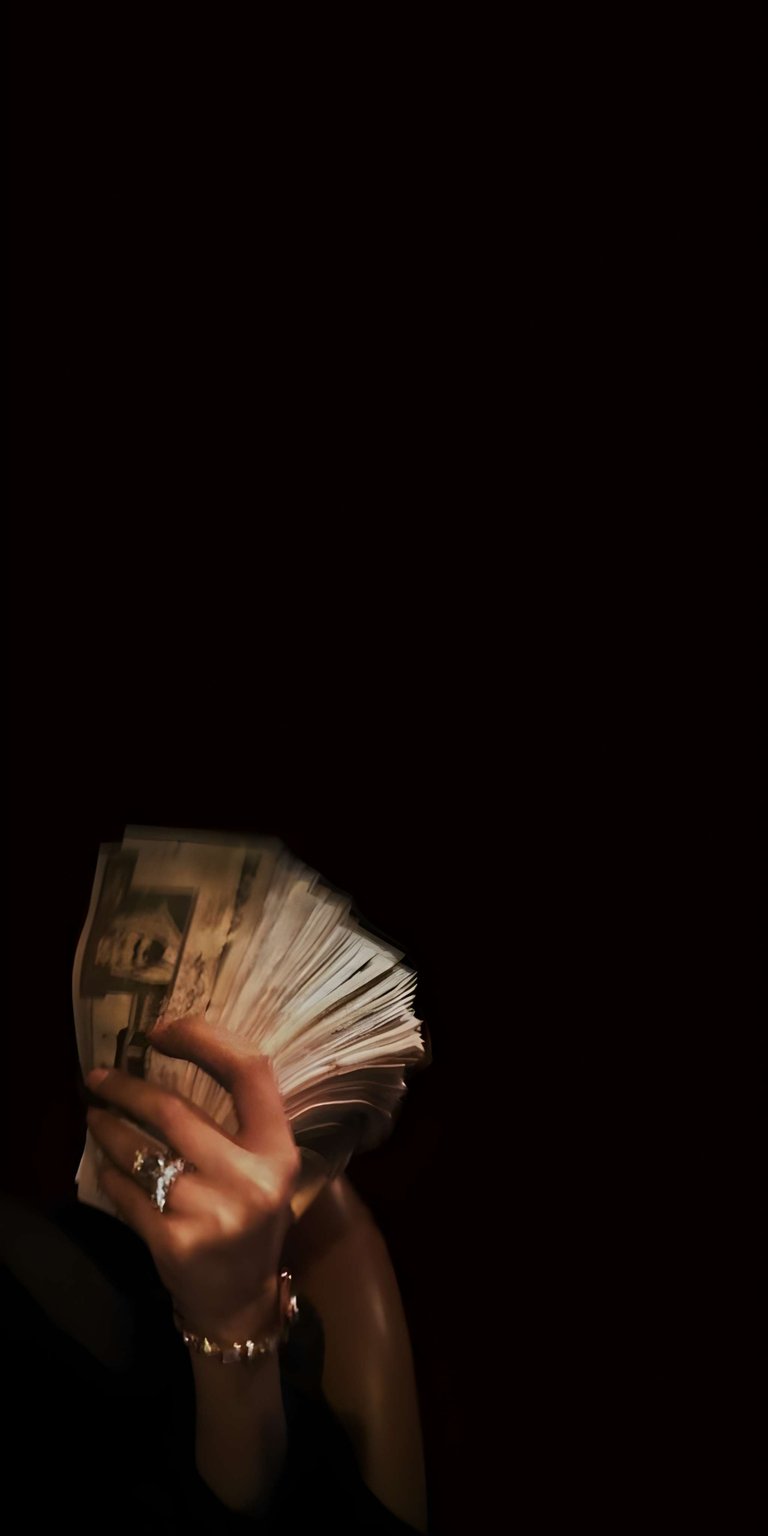 Money stack wallpaper designed as OLED / AMOLED wallpapers for iPhone, featuring a dramatic hand holding cash against a deep black background. This wallpaper uses low lighting, strong contrast, and a dark moody tone for an immersive lock screen and home screen wallpaper.