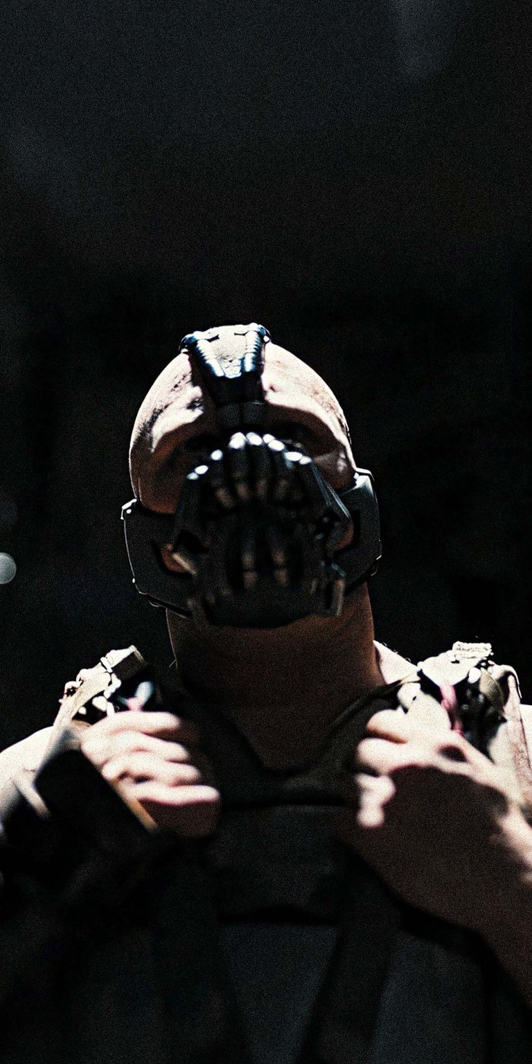 Download this amazing Bane 4K wallpaper for your iPhone, showing his iconic mask and muscular physique. This wallpaper captures the intimidating presence of the Batman villain.