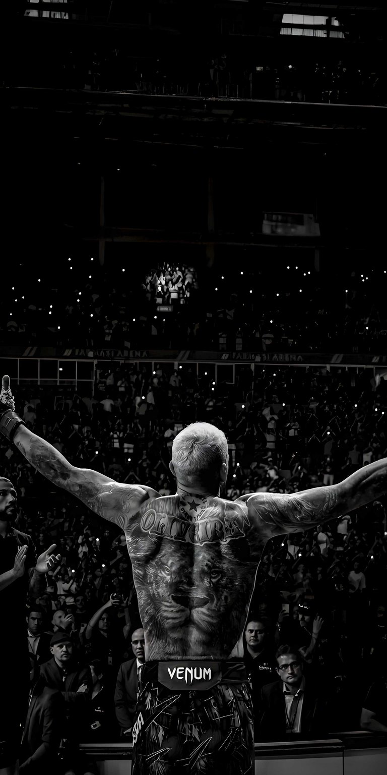 Get this incredible Charles Oliveira wallpaper for your iPhone, showcasing his tattoos and the roaring crowd. This 4K wallpaper captures the intensity of the moment with Oliveira's arms raised in victory and the bright lights of the arena.