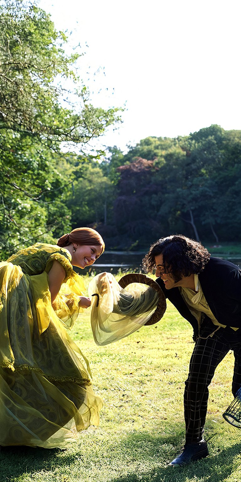 A serene, sunlit scene featuring characters from Guillermo del Toro's Frankenstein (2025), played by Mia Goth and Oscar Isaac, enjoying a moment in a lush park. The vibrant green gown and elegant period costumes create a beautiful, artistic aesthetic perfect for film lovers and those who enjoy a touch of gothic romance on their home screens. Ideal for iPhone, Android, and high-resolution displays.