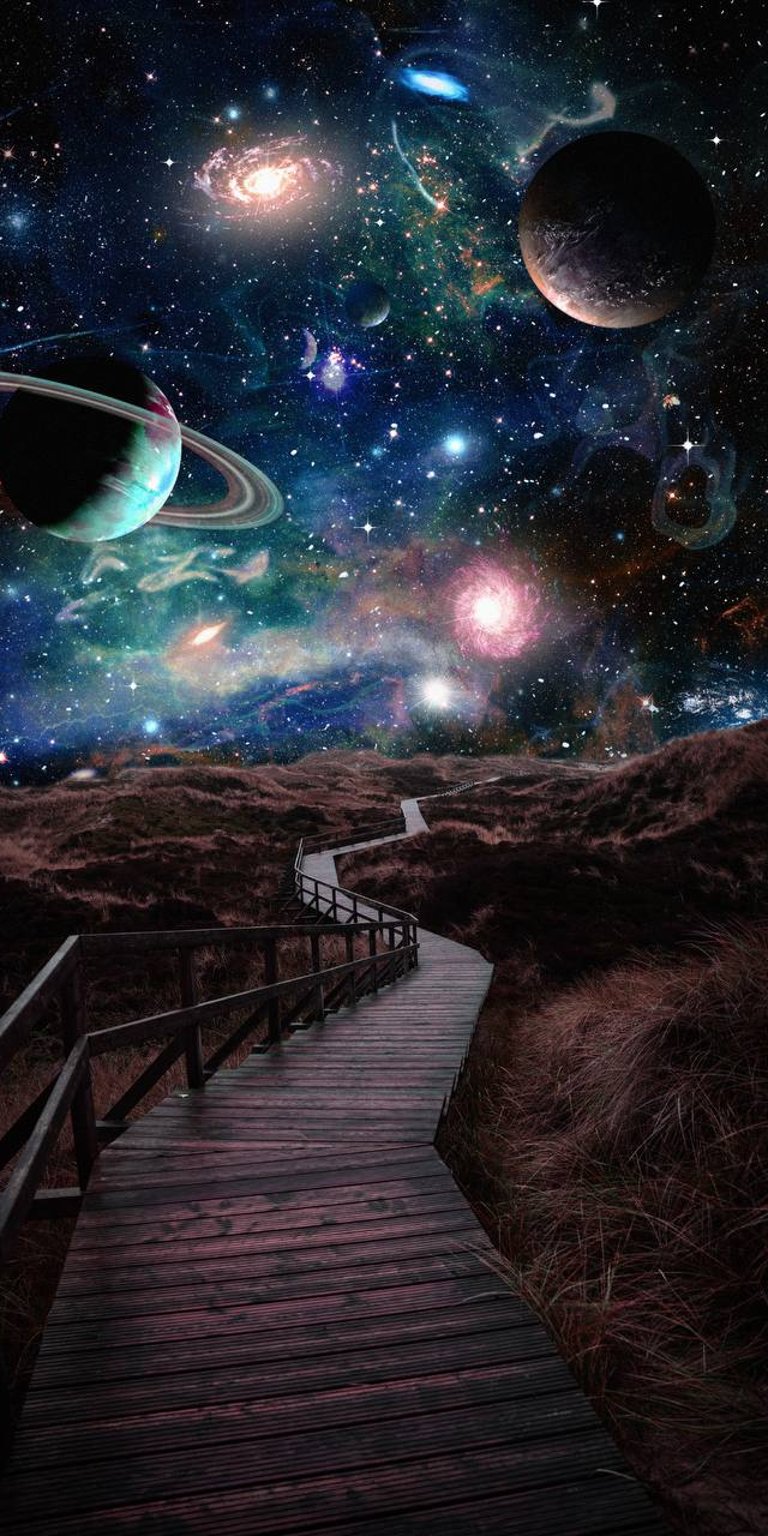 Wooden bridge on the field with edited galaxy planets view wallpaper