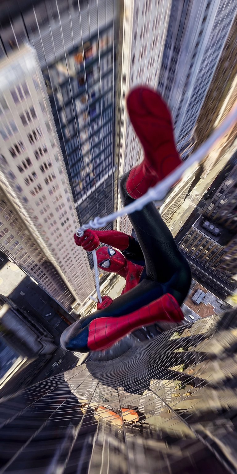 Grab this high-quality Spiderman 4K wallpaper for your iPhone today. Watch as Spiderman hangs upside down with a cityscape backdrop, and building reflections in the windows below.