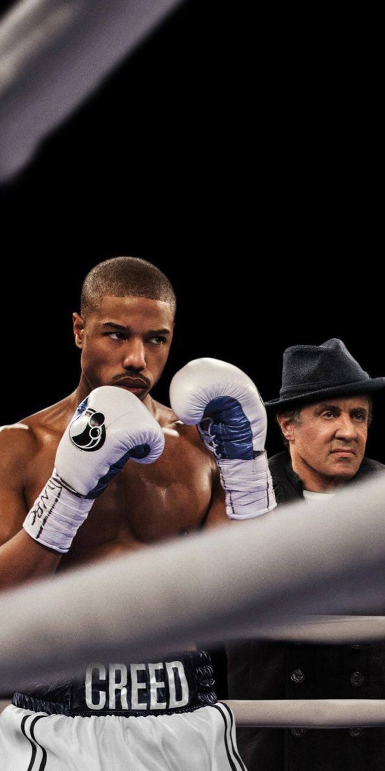 Adonis Creed in boxing ring with Rocky Balboa wallpaper