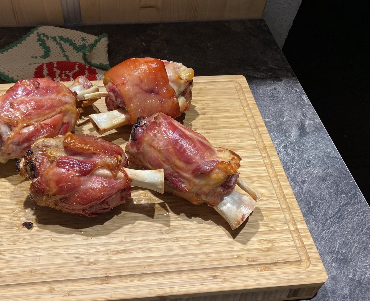 Vier knusprig gegrillte Schweinshaxen auf einem Holzbrett