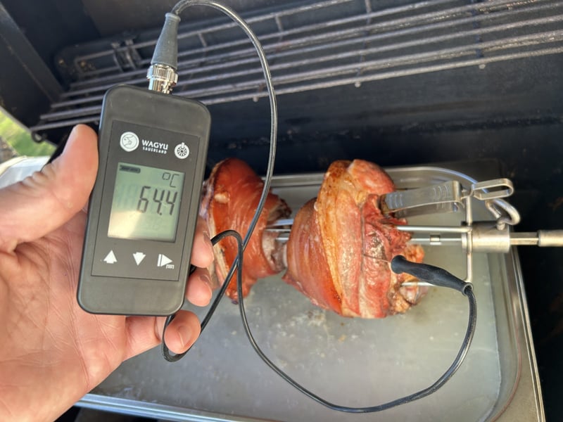 Fabians Kernthermometer zeigt 64,4&nbsp;°C, der Fühler steckt in Haxen am Drehspieß