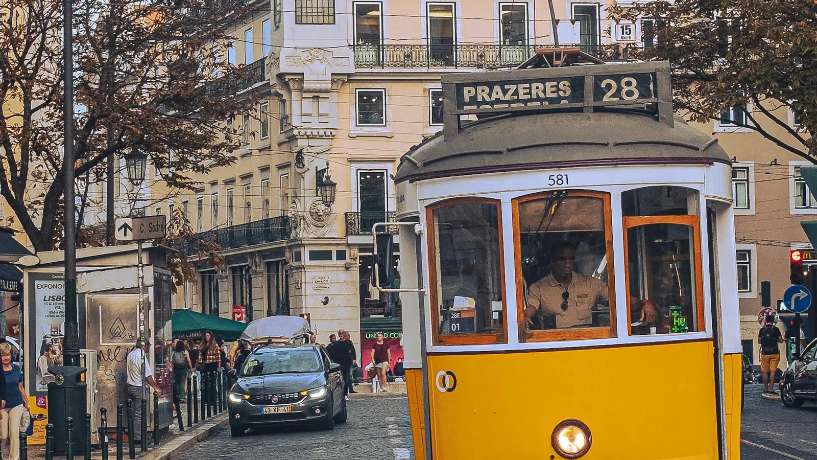 Historische gelbe Straßenbahn der Linie 28 Richtung Prazeres in einer Straße in Lissabon