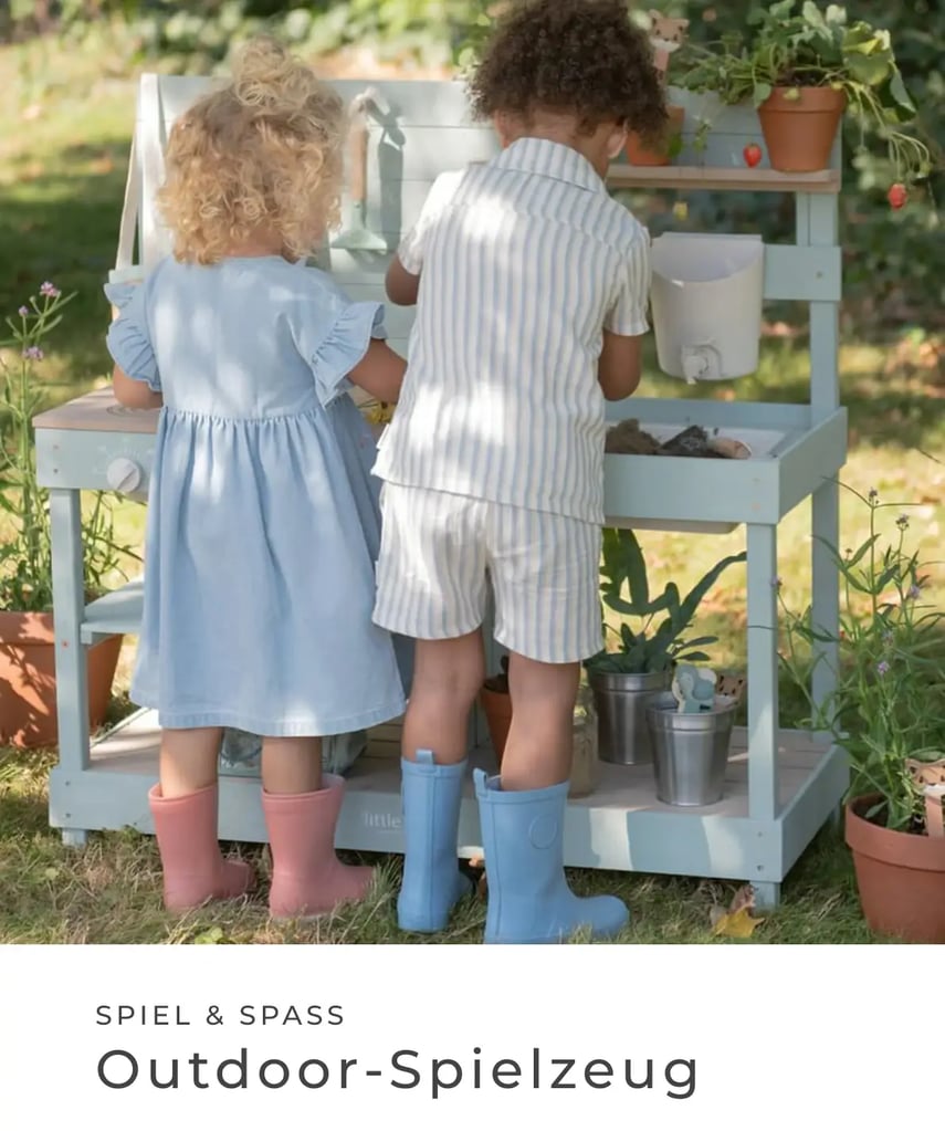 Zwei Kinder spielen im Garten an einer Outdoor-Spielküche und tragen Gummistiefel. Spiel & Spaß – Outdoor-Spielzeug.