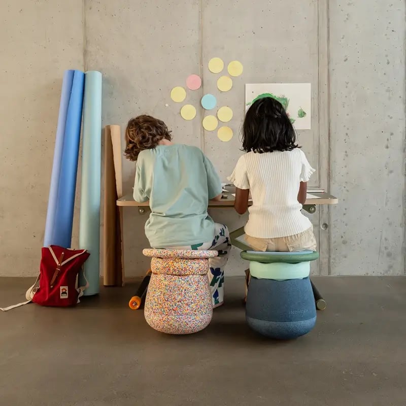 zwei Kinder sitzen auf Hockern aus Stapelsteinen