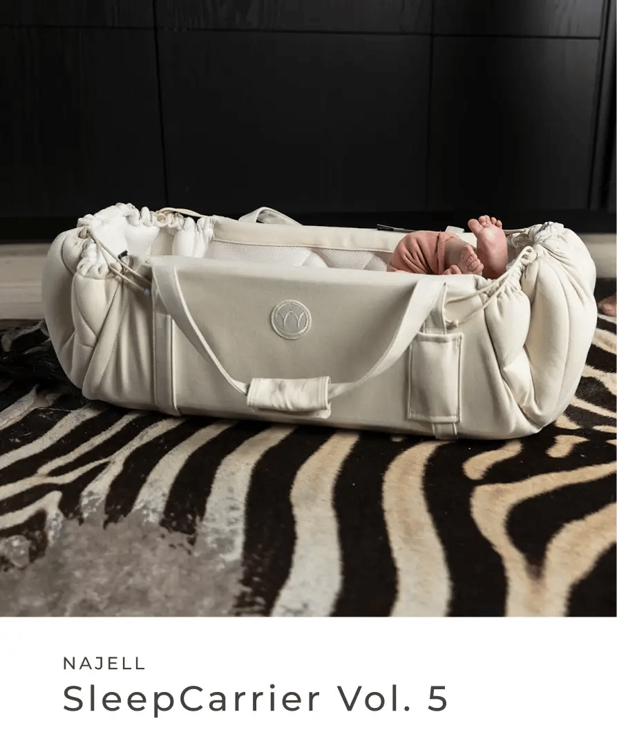 Baby liegt in einer hellen tragbaren Baby-Liege auf einem gemusterten Teppich. Najell: SleepCarrier Vol. 5.