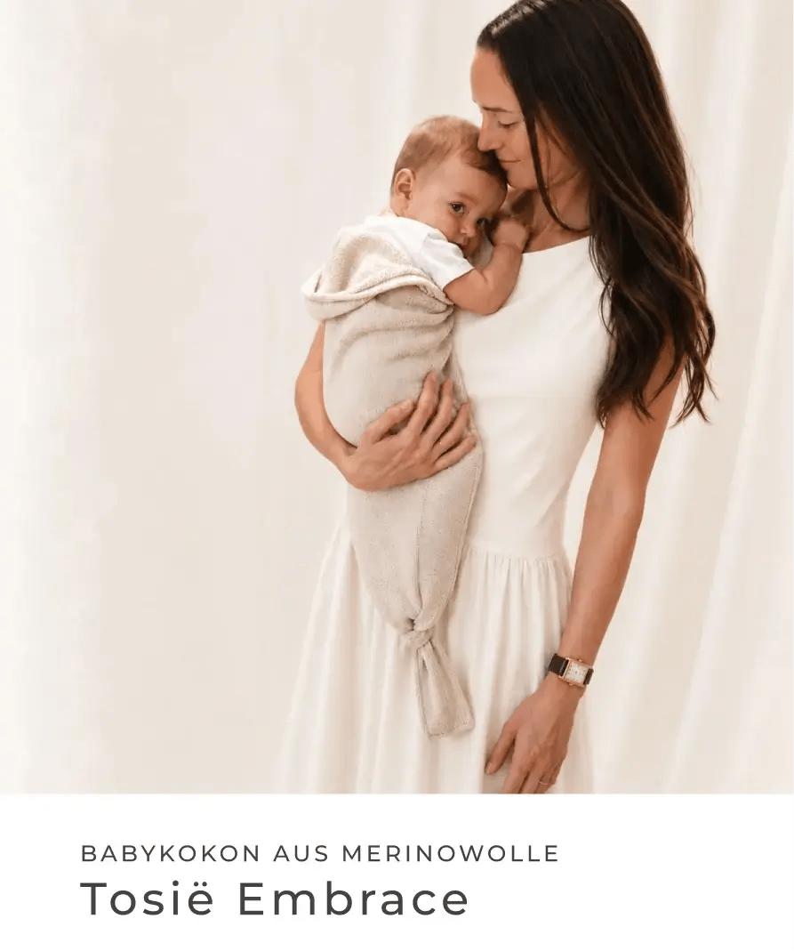Mutter hält ein Baby in einem hellen Babykokon im Arm. Babykokon aus Merinowolle: Tosiè Embrace.