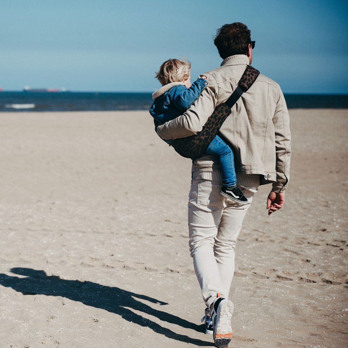 Wildride Kindertrage Lifestylebild Vater trägt Kind am Strand