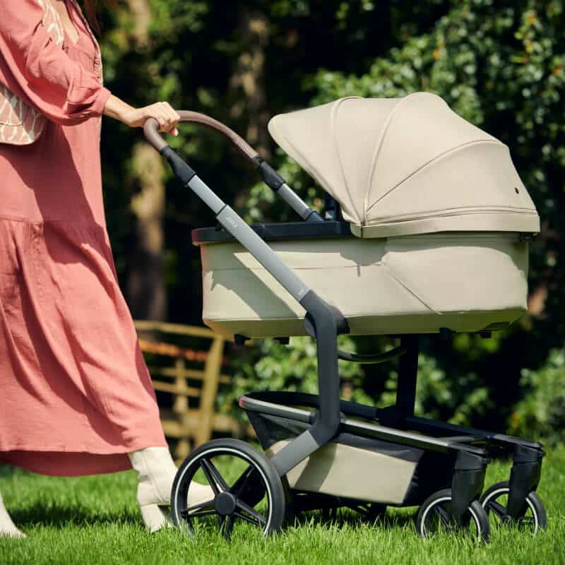 Frau schiebt den Kinderwagen Joolz Day 5 über eine Wiese