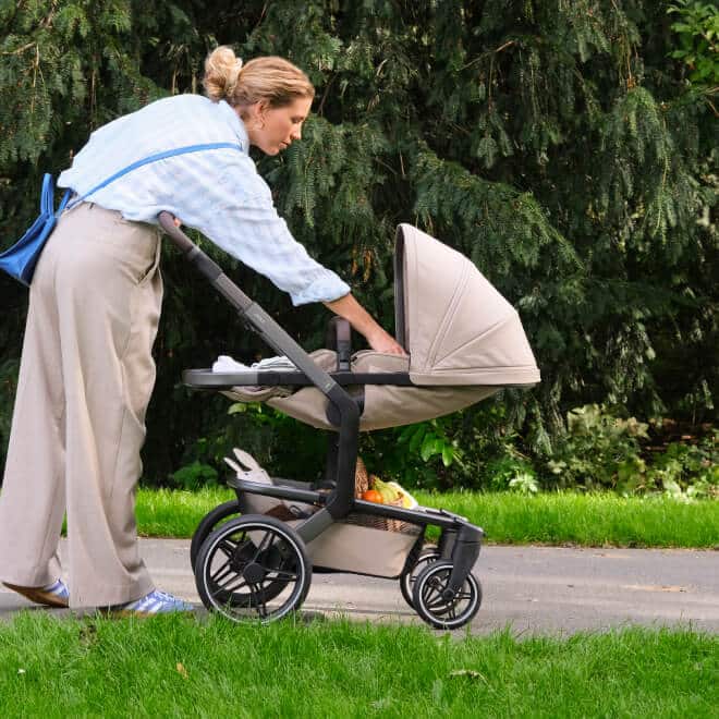 Eine Frau im Park kümmert sich um ihr Baby im Kinderwagen