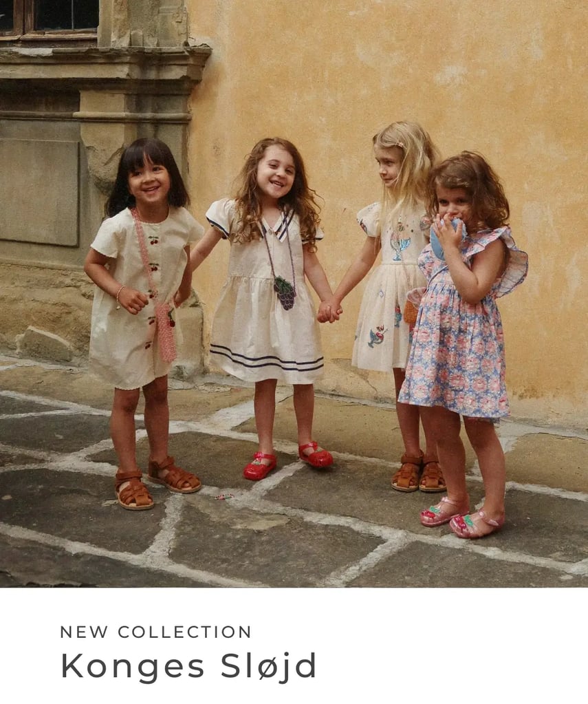 Vier kleine Mädchen in sommerlichen Kleidern stehen Hand in Hand vor einer warmen Hauswand und lächeln. Text im Bild: „New Collection – Konges Sløjd“